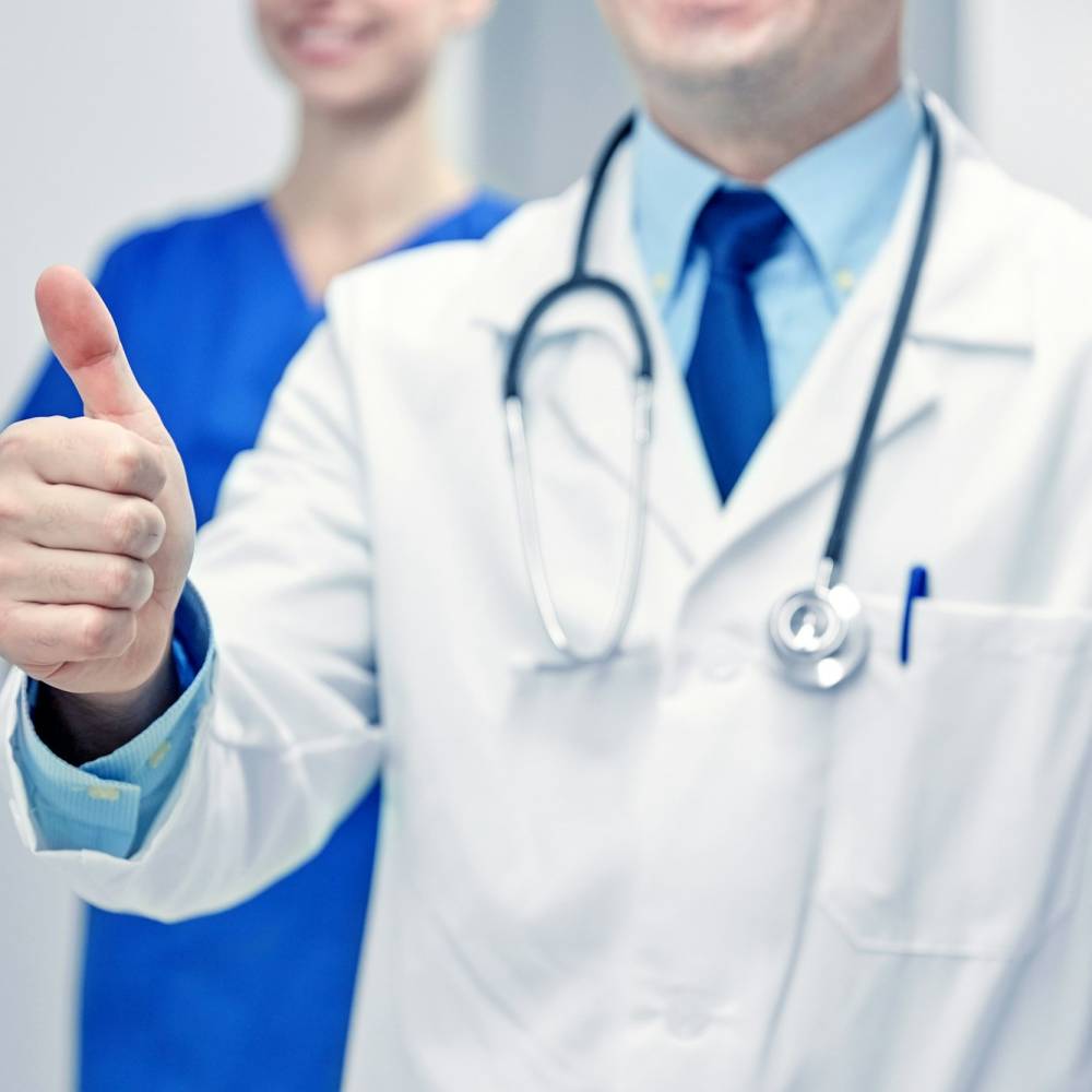 close up of doctors at hospital showing thumbs